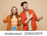 Small photo of Young couple two friends family man woman wear casual clothes point index finger aside on area mock up do winner gesture together isolated on pastel plain light beige color background studio portrait
