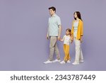 Small photo of Full body side view young parents mom dad child kid daughter girl 6 years old wearing blue yellow casual clothes hold hands walk go look aside isolated on plain purple background. Family day concept