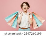 Small photo of Young amazed surprised shocked woman wear casual clothes hold shopping paper package bags look aside on area isolated on plain pastel pink color background studio. Black Friday sale buy day concept