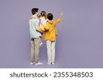 Full body back rear view young parents mom dad child kid girl 6 years old wearing blue yellow casual clothes hold daughter point finger aside isolated on plain purple background. Family day concept