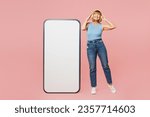 Small photo of Full body elderly woman 50s years old wears blue undershirt casual clothes big huge blank screen mobile cell phone smartphone with area listen to music in headphones isolated on plain pink background