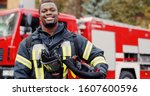Firefighter portrait on duty. Photo of happy fireman with gas mask and helmet near fire engine