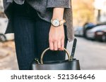 close up fashion details, young fashionable woman holding her bag. wearing golden jewelry, and white watch.
