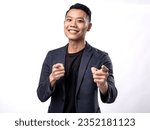 Small photo of A portrait of an Asian man wearing a black shirt and a dark blue suit, pointing in a certain direction with both hands, Isolated with a white background.