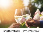 Small photo of Couple romantically celebrate outdoors with glasses of white wine, proclaim toast People having dinner in a home garden in summer sunlight.