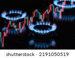 Small photo of Flaming gas burners on household kitchen stove with an exchange graph of the growth in the cost of natural gas prices