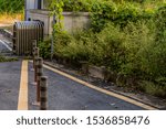 Small photo of Traffic bollards in front of metal folding entrance gate located in rural industrial park.