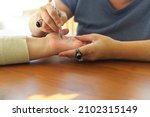 Small photo of Palm Reading. Chiromancer drawing life lines on plam of female client with red pen during palmistry or chiromancy session, cropped shot of palmist predicting future during fortune telling