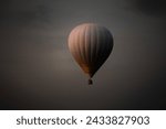 Hot air balloon with bright burning flame flying in the night.