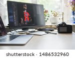 Professional photographer workspace.Photo retoucher work place in modern photostudio.Dslr camera,tablet with stylus for retouching images,big screen connected with notebook on table in sunny studio