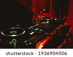 Small photo of Dj playing music on rave party in nightclub.Professional disc jockey plays concert turntables,sound mixer devices on stage in dark night club.Royalty free curated collection with parties and concerts