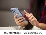 Woman browsing internet on mobile phone. Young adult female with long nails using modern blue smartphone with triple camera