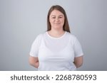 Cheerful plus size model posing in studio. Young Caucasian overweight woman wearing white t-shirt looking in camera with a smile