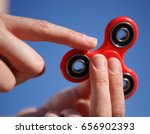 Cool new fidget spinner toy.Woman play with modern spinning device.Enjoy playing with  trendy gadget with rotating bearing in the middle.Bright blue sky background.Most popular spinner gadget in 2017