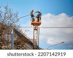 Small photo of Workers on lifting platform installing new LED lamps. Electrician work service mounting street lighting. Workers installing LED lights. Replacement of old incandescent lamps with new LED lamps