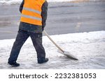 Man clear snow from sidewalk, cleans footpath from snow during blizzard. Utility worker shoveling snow on city street. Janitor clearing snowy walkway with shovel.