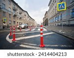 Pedestrian crossing sign and orange pole installed on crosswalk, road markings on zebra crossing. Traffic bollards on roadside, prevent parking car near pedestrian crossing. Selective focus