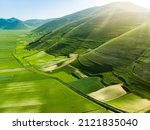 Aerial view of Piano Grande, large karstic plateau of Monti Sibillini mountains. Beautiful green fields of the Monti Sibillini National Park, Umbria, Italy.