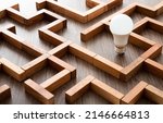 Small photo of Light bulb in the maze game built by wood blocks, finding the right way to the success, searching creative idea concept