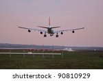 Airplane with four engines landing on runway back view
