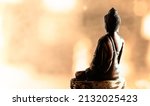 Back side of meditating Buddha statue. Bokeh background. Warm colors. Peace of mind concept