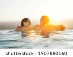 Rear view of couple relaxing in infinity pool at resort