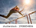 Small photo of Runner jumping over running hurdle, low angle view