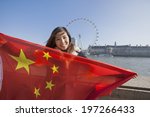 Portrait of happy young woman holding Chinese flag; England; UK