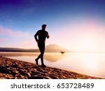 Man running at seaside twilight time. Runner athlete running at seaside. Sportsman fitness silhouette sunrise jogging workout wellness concept. 