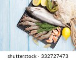 Fresh raw sea food with spices on stone plate over wooden table background. Top view with copy space