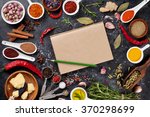 Notepad for your recipe with herbs and spices over black stone background. Top view with copy space