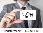 Social media hashtag. Businessman in suit with a black tie showing or holding business card