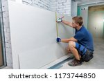 man measuring plasterboard sheet for interior construction