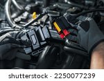 Small photo of mechanic installing chip tuning box on car engine