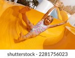 happy cheerful child on slide at outdoor water park. summer vacation