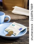Small photo of Restaurant tips or gratuity, euro banknotes and coins on plate