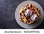 Plate of belgian waffles with chocolate sauce and ice cream on dark gray background. From top view