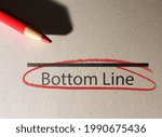 Small photo of Bottom Line text circled in red pencil on textured paper surface