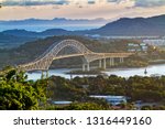 Panoramic aerial view of the Bridge of The Americas over the Panama Canal Pacific Entrance. Sunset scene with a gentle mist in the background. The bridge is spanning two continents - two Americas.