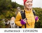 Happy smiling woman hiking in mountains with akita dog, Karkonosze Mountain Range. Young female hiker smiling, sport and trekking in autumn nature.