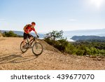 Mountain biker riding on bike at the sea and summer mountains. Man rider cycling MTB on country road or single track. Sport fitness motivation, inspiration in beautiful inspirational landscape.
