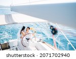 Small photo of The bride and groom stand at the helm of the yacht sailing in the sea and embrace