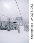 Small photo of Chairlift with skiers ascends a snowy slope in the Kolasin 1600 resort. Montenegro