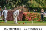Small photo of JEKYLL ISLAND, GA, USA/MARCH 20, 2019: A senior croquet player prepares to strike his ball between a senior woman player and a younger scorekeeper at Jekyll Island Club.