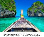 Traditional wooden longtail taxi boat nose with decoration flowers and ribbons at Maya Bay beach against steep limestone hills. Main Thailand tourist attraction background, Ko Phi Phi Leh Island