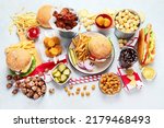 Small photo of Various of american food, French fries, hamburgers, nuggets, hotdog, chips, popcorn, sauces on a white background, top view.