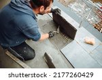 workers hands installing ceramic tiles on the balcony floor. a handyman using a tile spacer to adjust the tile level. Repair work, construction details