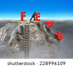 businessman pushing red fear word down with dollar sign and wooden ladder on top of rocky mountain, overcoming fear concept.