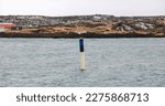 Small photo of Black yellow spar buoy with light on top. Navigation equipment of Reykjavik harbor, Iceland