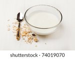 Bowl of yogurt with muesli and silver spoon on white table